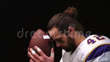 美国足球运动员，在比<strong>赛前</strong>轻轻地握住并亲吻他的球，并在精神上念着祈祷