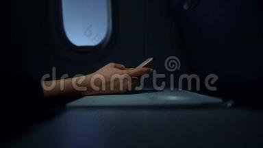 一个无法辨认的女人的手，坐飞机在智能手机屏幕上打字。 实时关闭