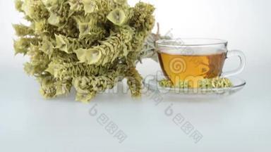 一大堆山茶马洛提拉和杯子与温暖的茶。 希腊传统草药。 白色背景的希腊山茶