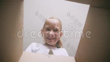 惊讶的女孩打开纸箱，打开纸箱，看里面。 儿童情感概念。