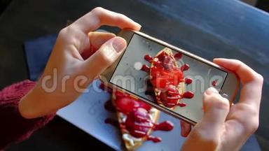 女人用智能手机`美丽的开胃甜点拍照。