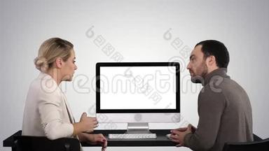 <strong>商务</strong>人士在电脑显示器周围开会，<strong>谈论</strong>梯度背景下屏幕上的内容。