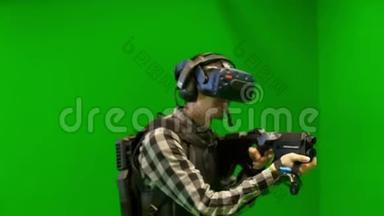 男人在绿色背景下在虚拟现实中玩射击。 虚拟现实耳机测试VR射击游戏