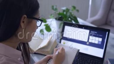远程在线学习，学生女孩使用笔记本电脑设备，并在记事本中绘制一个图形，坐在咖啡馆的桌子上。
