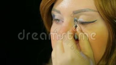 化妆室里的红发女演员用银色的影子做眼妆，准备<strong>上台</strong>
