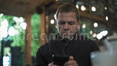 一个悲伤的人在智能手机上观看照片，坐在夜店等待约会