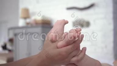 宝宝的双脚在妈妈<strong>关爱</strong>的手中紧紧地贴着妈妈，刚出生的女孩在尿布上积极地移动着躺在换尿布的桌子上