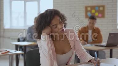 瘦弱的朴素女人睡在讲座里。 黑女孩突然惊醒。 背景学生组