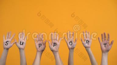 支持橙色背景下的书面手掌，团队合作，<strong>积极分子</strong>