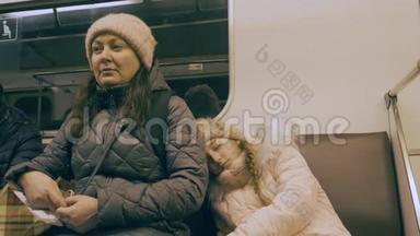 疲惫的妈妈和熟睡的女儿在现代城市的地铁里开车