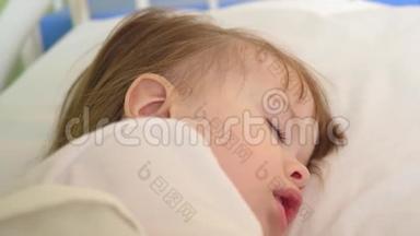 小婴儿睡在医院病房的白色床上用品。 在医院治疗儿童。 生病的孩子