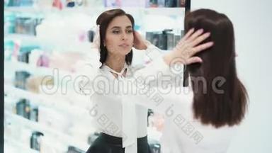 在化妆品店里，漂亮的年轻女子在镜子前打扮自己