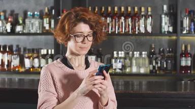 站在<strong>酒吧</strong>间附近的<strong>餐馆</strong>里，一个红发女人在使用智能手机
