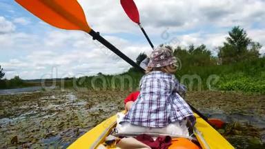 一个小孩用皮划艇划桨。 积极的家庭度假。