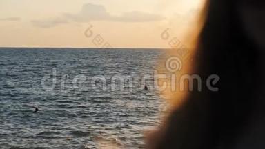 飘扬的头发。 日落时海上的女孩