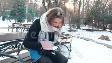 漂亮的年轻女子在笔记本上做笔记的肖像留在公园里，在笔记本上做笔记
