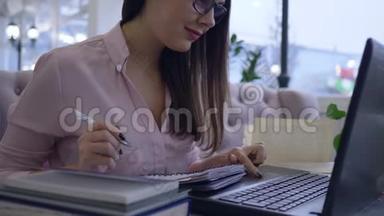 远程教育，快乐的学生女孩用笔记本电脑工作，用笔记本电脑做笔记，坐在