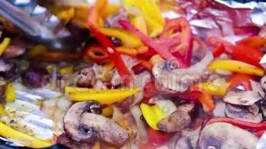 红椒和黄椒用火钳转动，用洋葱、蘑菇和调味料烤在热炭上