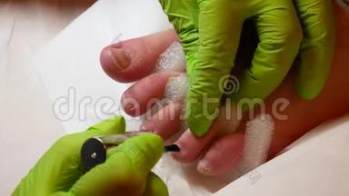 一个年轻漂亮的女孩坐在椅子上，在美容院，她被给予修脚。 绿色指甲大师手