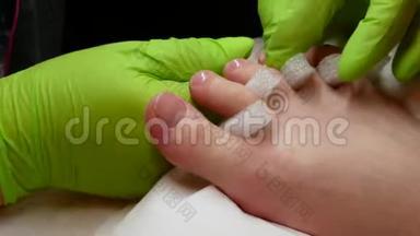 4K美容和水疗的概念。 掌握绿色手套的修脚检查客户指甲上底漆的质量。