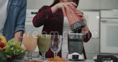 一对年轻的纯素食夫妇在早上为所有的家庭做<strong>冰沙</strong>，女人把<strong>冰沙</strong>倒进一个大玻璃杯里，放在一个大玻璃杯里
