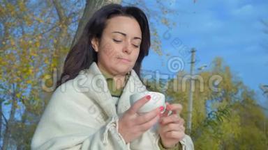 特写镜头，美丽的女人在格子里手捧一杯茶在城市公园和看日出