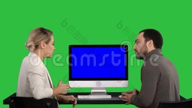 商务人士在电脑显示器周围开会，谈论绿色屏幕上屏幕上的内容，Chroma