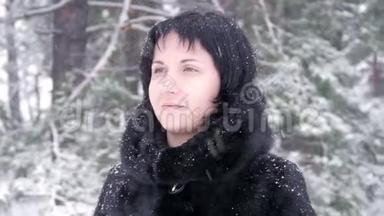 一个穿着毛皮<strong>大衣</strong>的黑发女人站在一个<strong>冬天</strong>的公园里，缓慢地看着飘落的雪。