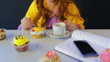 桌旁咖啡馆里的女孩喝茶，<strong>用勺子</strong>吃蛋糕。