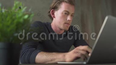 微笑的商务年轻人坐在电脑前，在笔记本电脑上打字。 帅哥商人发短信说