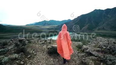 穿着橙色雨衣的女旅行者来到<strong>山崖</strong>边。 背面