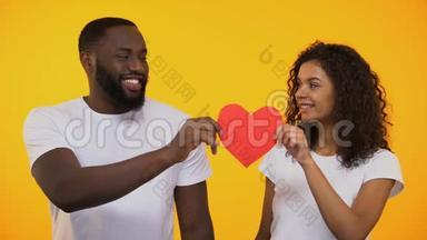 幸福的多民族夫妇捧着红纸心，微笑着，真爱真关怀