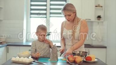 一位年轻美丽的白种人母亲留着白发，儿子在明亮的厨房<strong>做饭</strong>。 妈妈教儿子<strong>做饭</strong>。