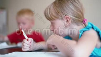 女孩和男孩在家里的办公桌上用<strong>彩色铅笔画</strong>纸
