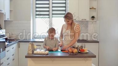 一位年轻美丽的白种人母亲留着白发，儿子在明亮的厨房<strong>做饭</strong>。 妈妈教儿子<strong>做饭</strong>。