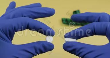 一个椭圆形和一个圆形的白色药丸，手中穿着蓝色医用手套