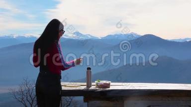 女人吃三明治，喝茶，以抵御山岳景观