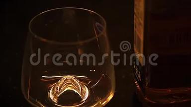 波旁酒、白兰地或威士忌的微光镜头倒在黑桌上的酒杯里。