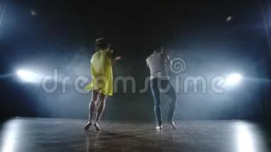 一个男人和一个女人一起跳舞，一个穿着牛仔裤的滑稽舞蹈和一条黄色的裙子在舞台上冒烟。 <strong>音乐剧</strong>
