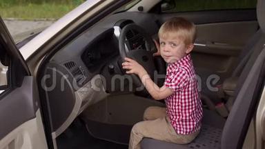小男孩坐在驾驶座`轮子后面，他玩转轮子。