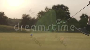 高尔夫球躺在草地上晒太阳. 不认识的成熟男人用高尔夫球杆移动球。 夏季