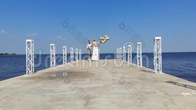 空中视频，美丽的新婚夫妇，新娘和新郎在户外跳舞，在一个美丽的码头，在<strong>蔚蓝</strong>的<strong>大海</strong>和