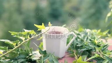 热气腾腾的茶或咖啡杯在常春藤覆盖的阳台栏杆上。 晨饮<strong>远眺</strong>群山..