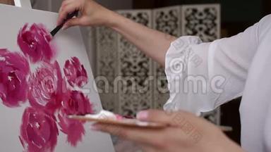 特写女孩用画笔在画布上画牡丹，特写。