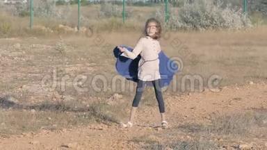 难民女孩在难民营的垃圾地上玩耍。 女孩手里拿着毯子跳舞。 贫穷和幸福概念