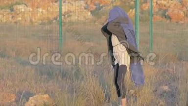 奇怪的小女孩走在难民营里，用蓝色的毯子覆盖着寒冷。 边境地区移民儿童住宿地