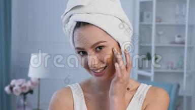 一幅美丽的年轻女子的肖像，头上有毛巾，用<strong>遮瑕</strong>膏。