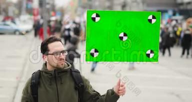 年轻人正在看<strong>海报</strong>，手里拿着绿色的屏幕在城<strong>市集</strong>会上。