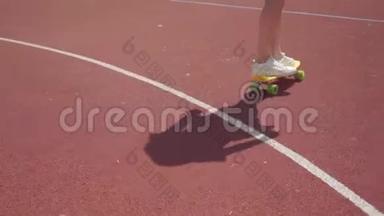 在<strong>户外</strong>篮球场上，穿着白色<strong>运动鞋</strong>的女孩子骑着黄色滑板特写。 影影随形