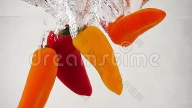 许多新鲜的、五彩斑斓的红椒甜椒掉进水里，溅起泡泡